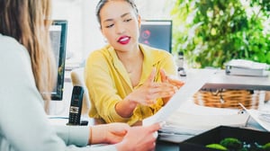 A woman pointing to a stack of papers